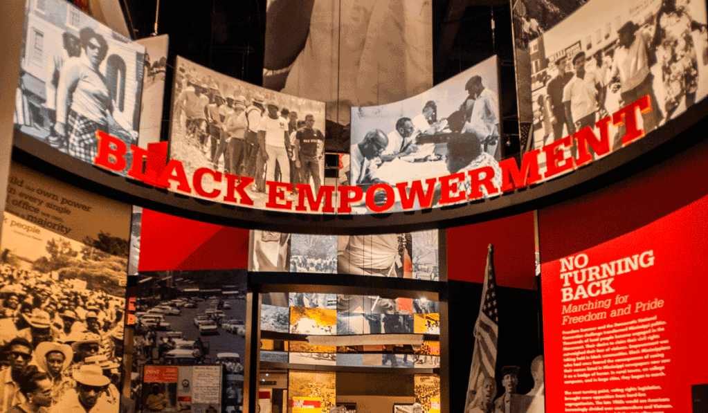 A museum display showing a lot of old black and white photos with large red text signage, the top one reads Black Empowerment