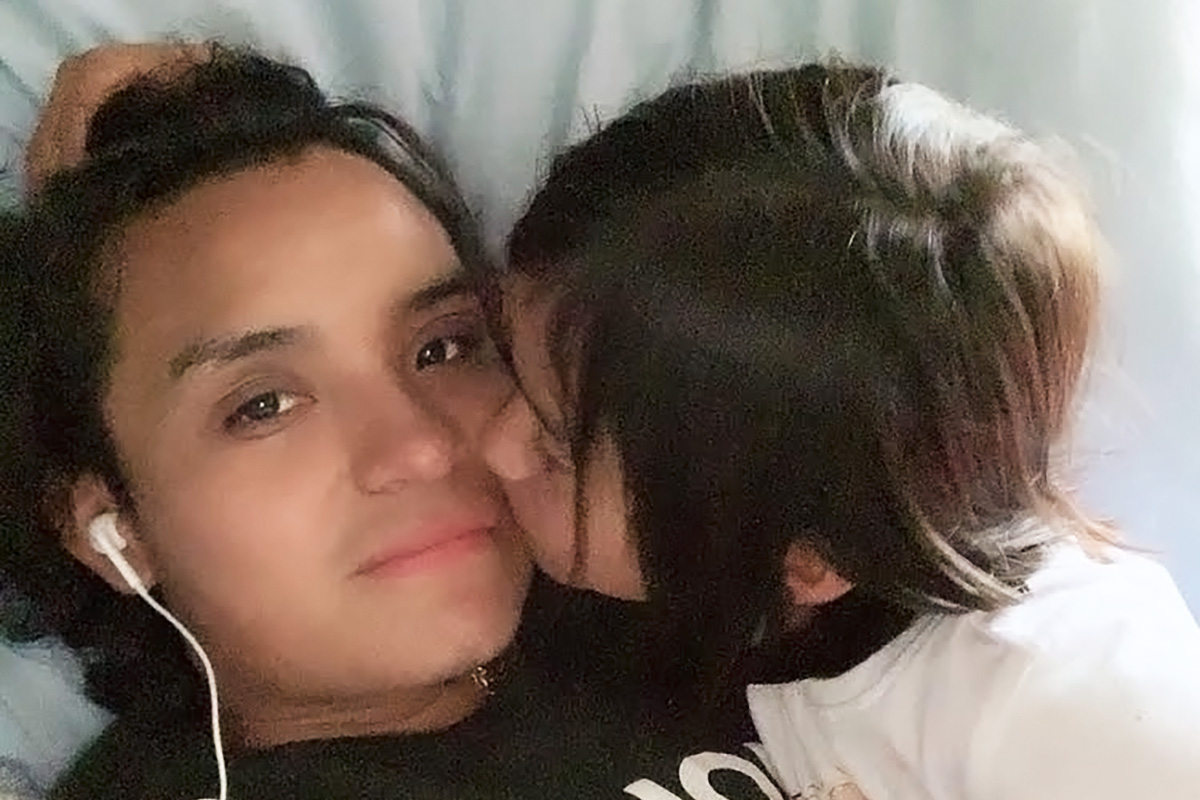 Salomon Diego Alonso lies in bed while his small daughter kisses his cheek