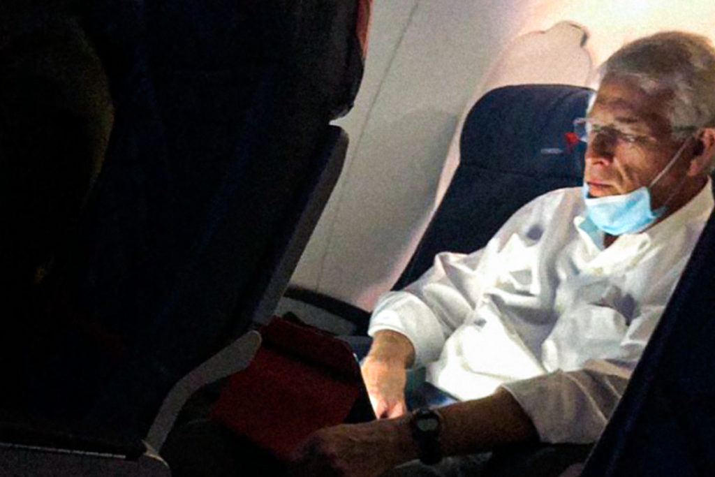 Sen wicker sits on a plane with his mask hanging under his chin