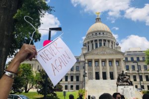 abortion hanger with the sign "Never Again" hanging from the bottom at Mississippi Capitol