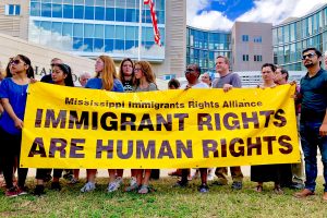 A dozen supporters of immigrants rights hold a yellow banner saying: "IMMIGRANT RIGHTS ARE HUMAN RIGHTS" outside the federal courthouse in Jackson