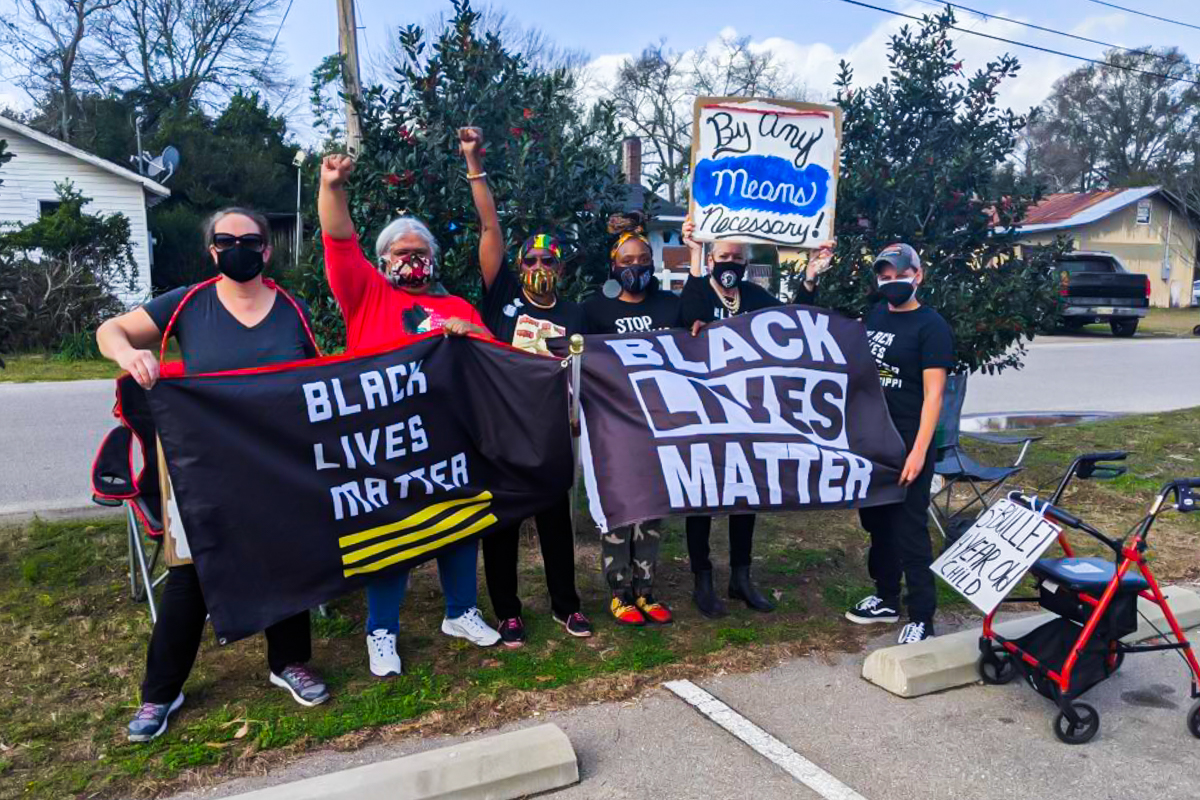 A multiracial group of women with Black Lives Matter Mississippi protest near the side of the road over the police killing of a 14-year-old.