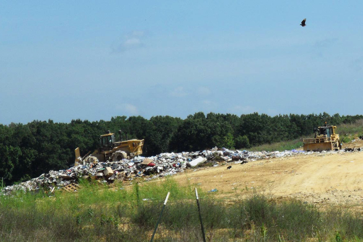 Two tractors pushing garbage on a hill
