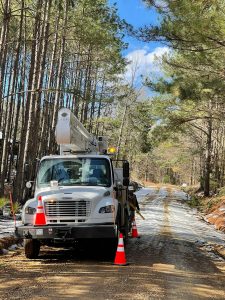 Entergy Utility Truck parked on a ice covered gravel road lined with tall pine trees