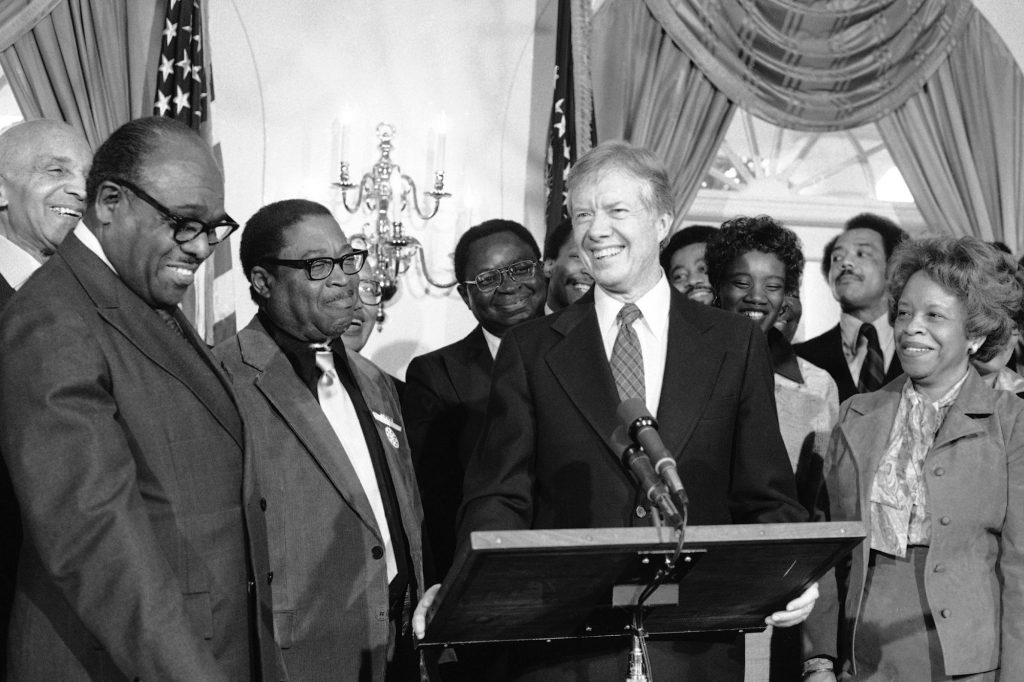 Jimmy Carter at a podium surrounded by people