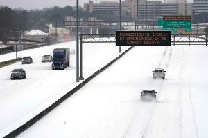 A snowy vide of the interstate with a warning sign above
