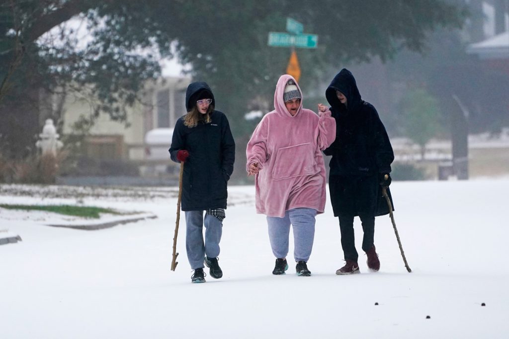 Three women walking down a road covered in snow