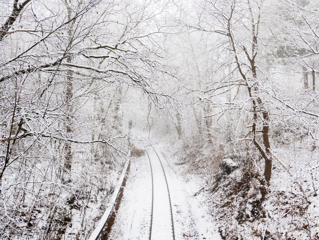 A stock photo of a snowy train track in the woods 