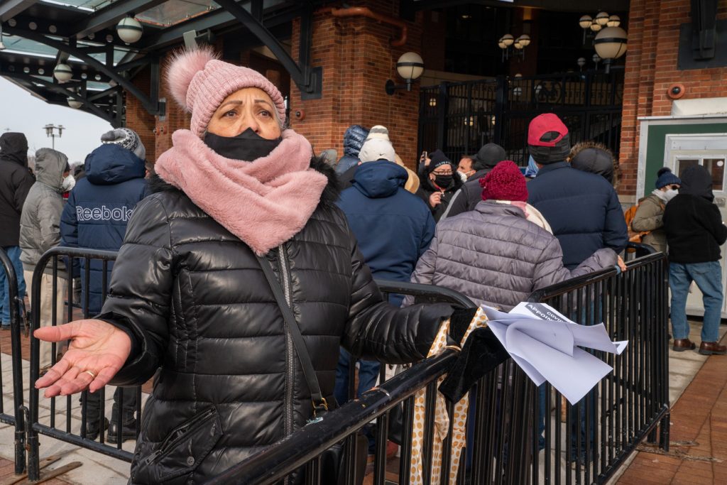 A woman holds up paperwork in frustration outside a stadium vaccine site