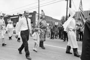 Parade of KKK members and a little girl marching