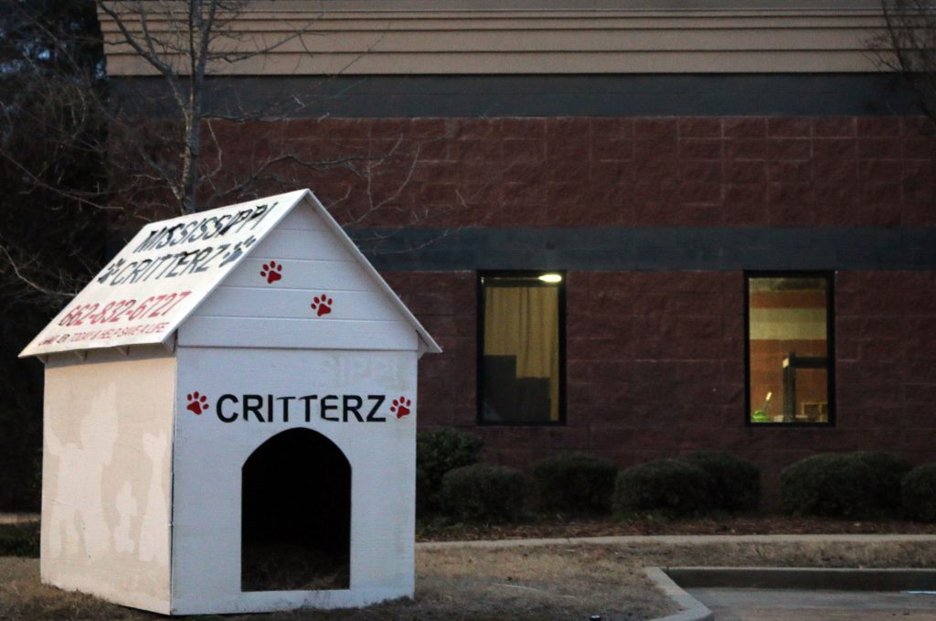 A white doghouse with the Mississippi Critterz name painted on it sits outside the shelter