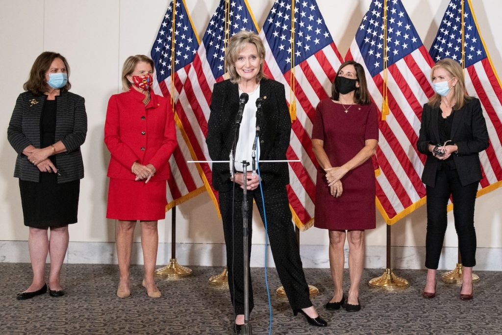 Senator Cindy Hyde-Smith speaks at a podium with Republican women behind her
