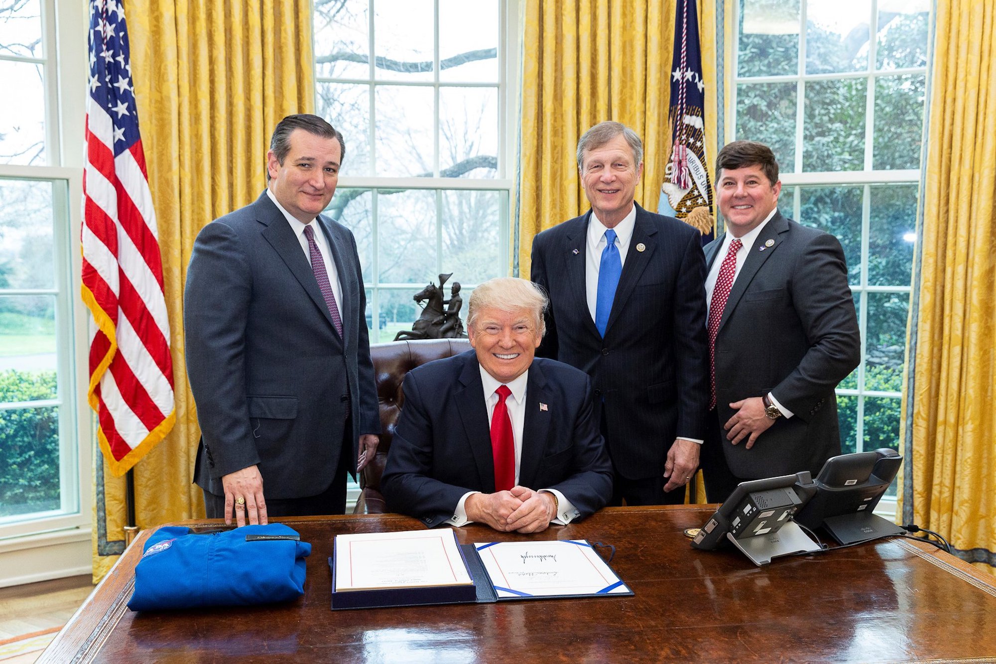 Steven Palazzo and Ted Cruz stand near then-president Trump in the Oval Office at the resolute desk