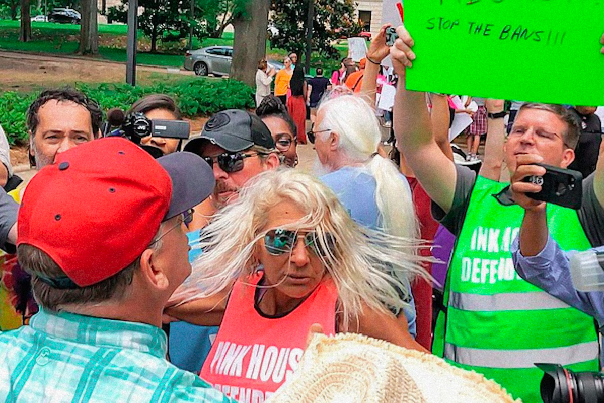 Derenda Hancock holds her arms out to separate the crowd of abortion rights activists separated from protester Coleman Boyd as the two sides yell at one another