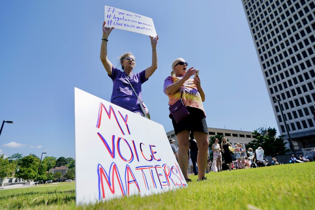 a protester waves a sign outside the Mississippi Supreme Court building. A sign at her foot says, "My voice matters"