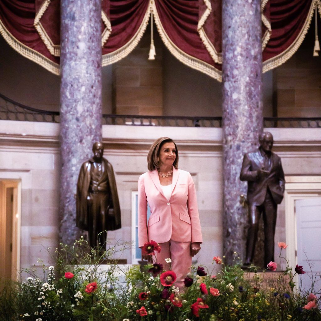 Nancy Pelosi stands in front of two statues in the Capitol