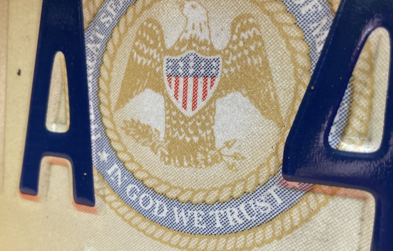 A Mississippi license plate containing the State Seal with the words "In God We Trust"