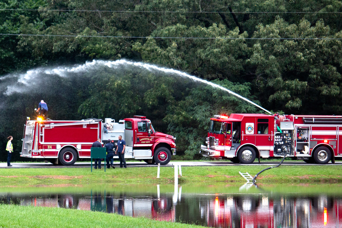 Fire trucks pumping water beside a flooded area