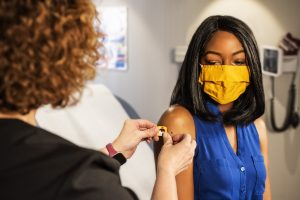 Woman applying bandage to vaccination spot