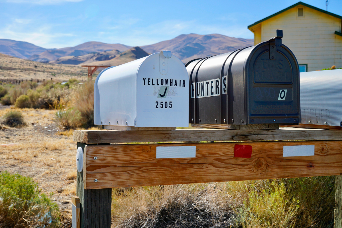 A set of mailboxes, one white on the left reading "Yellowhair" and one in black on the right reading "Hunters"