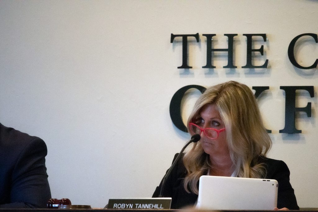 Oxford Mayor Robyn Tannehill at the front table at an Oxford Board of Aldermen meeting looking over her red-frame glasses with a laptop in front of her