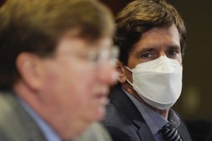 Mississippi State Health Officer Dr Thomas Dobbs looks at Governor Tate Reeves while wearing a mask during a press conference. He is now concerned about the Delta variant that is spreading in the state