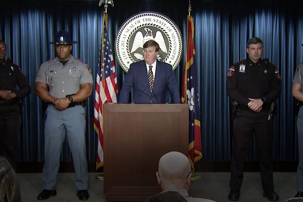Tate Reeves at podium with uniformed officers on either side