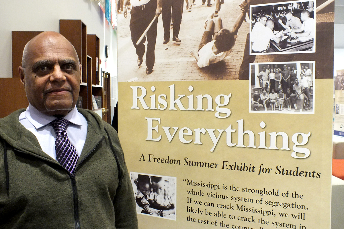 Bob Moses standing in front of a Freedom Summer exhibit banner
