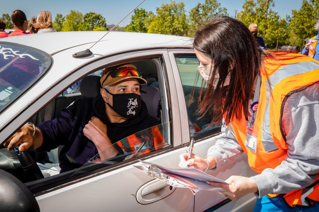 Masked man in car driving through a vaccination line