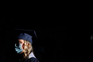 a student with a blue ole miss graduation cap is seen with a mask