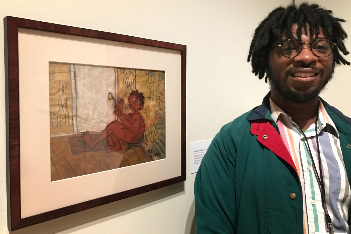 Brenden Davis standing beside his artwork in a museum
