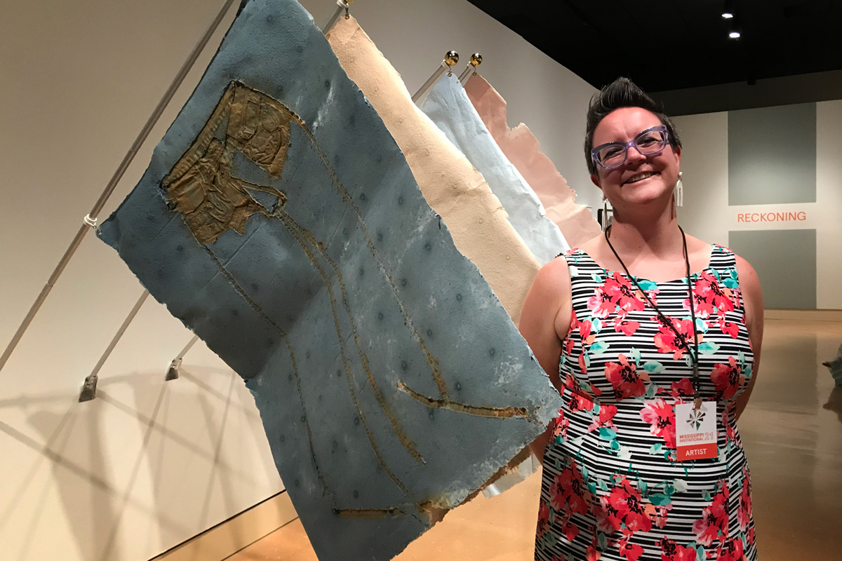 Kristen Tordella Williams standing by her artwork in a museum