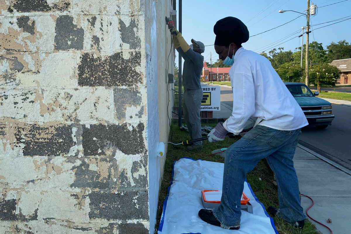 Leo Carney and Laronne Lewis painting the side of a brick building