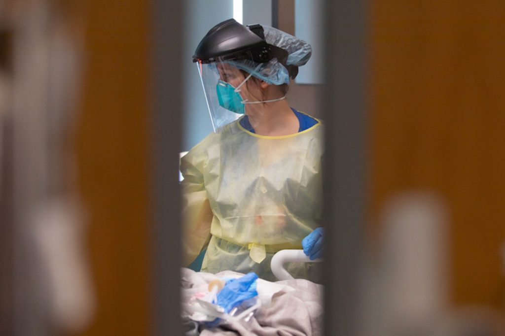 A nurse checks on a pediatric Covid patient wearing full PPE