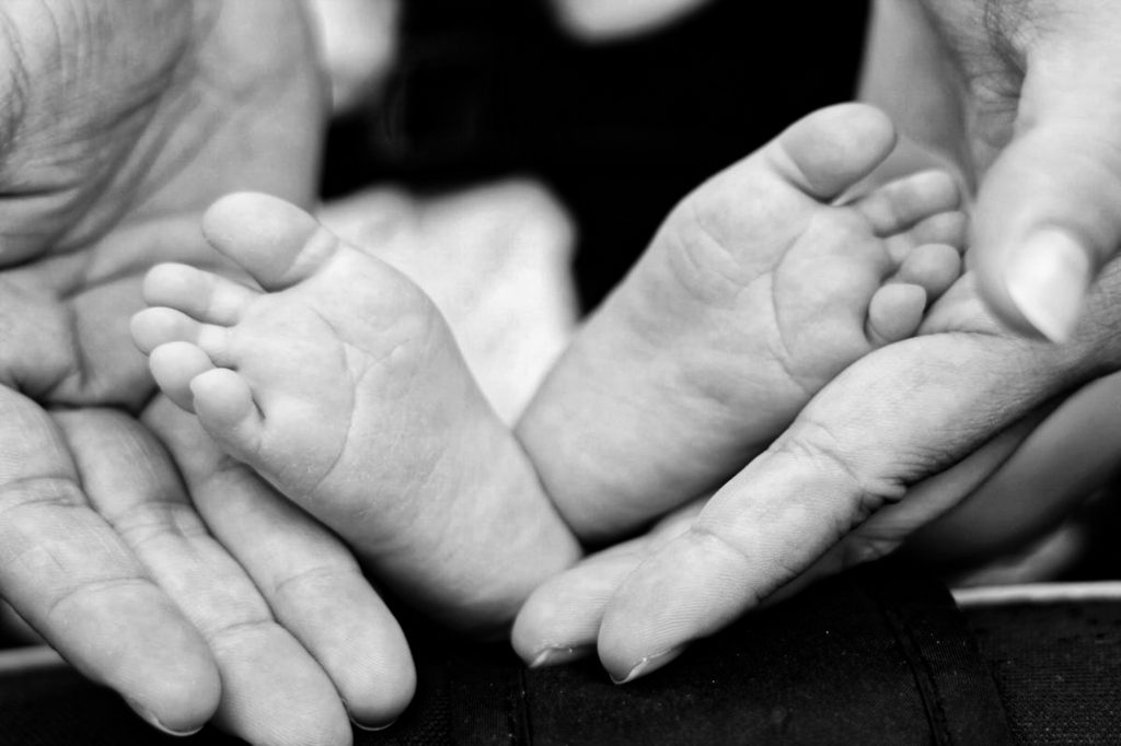 photo shows hands holding a baby's feet