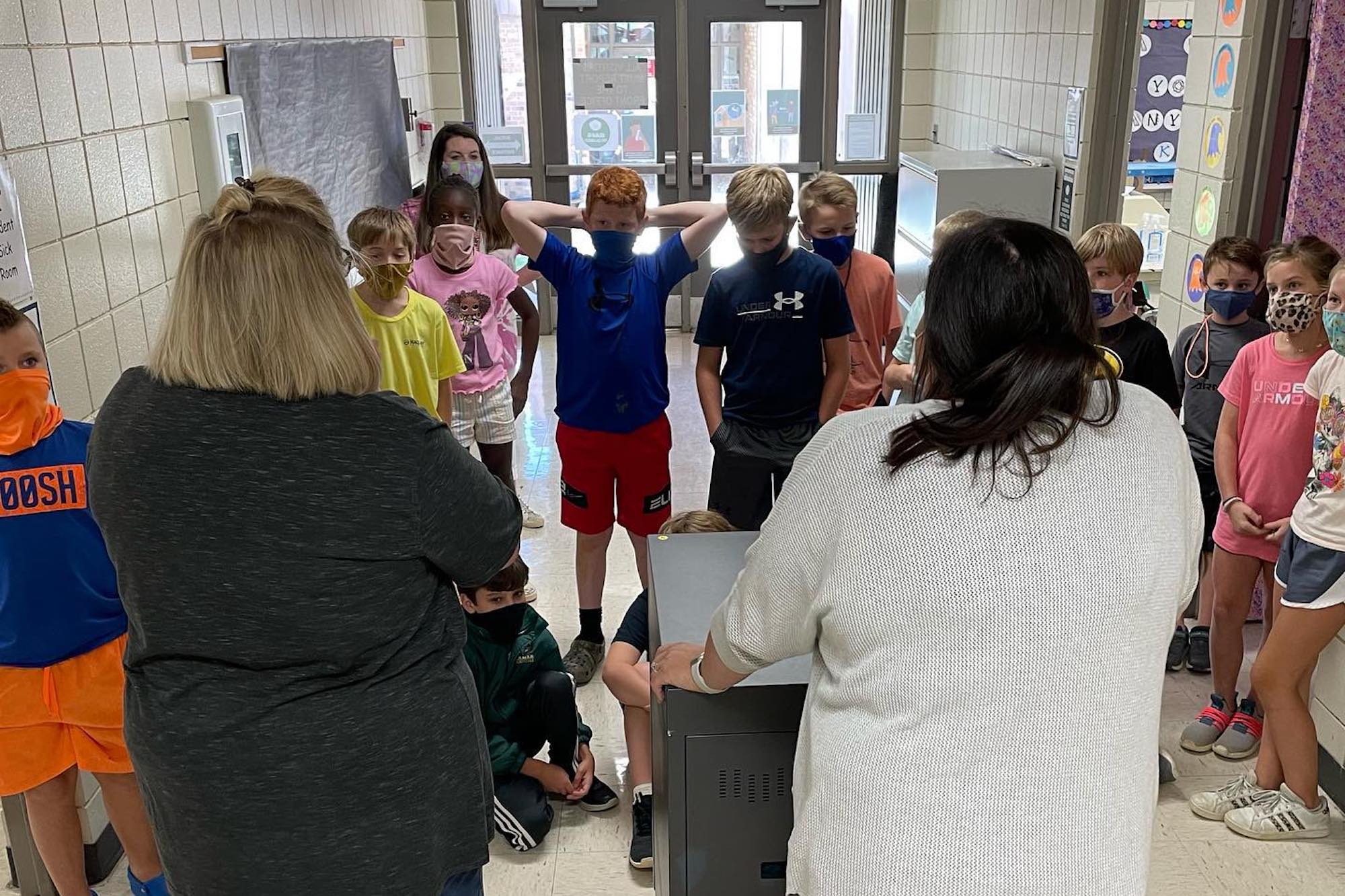 children in masks stand in a hallway facing two teachers in the Rankin County school district