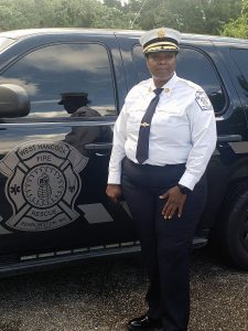 Deedra Burton in formal firefighter wear standing in front of a West Hancock Fire and Rescue vehicle