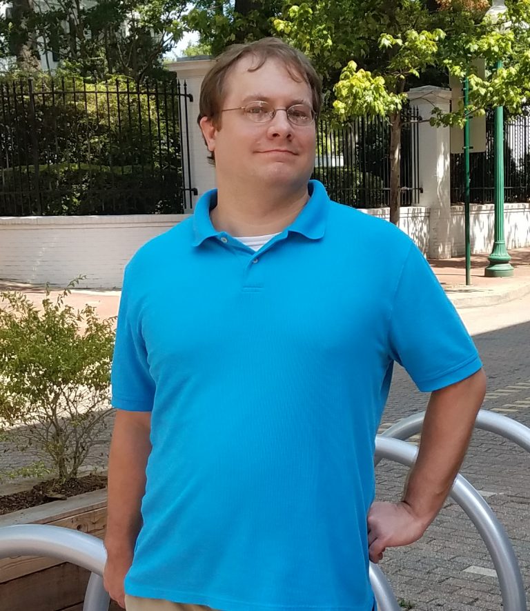 Man in bright blue polo shirt with hand on his hip