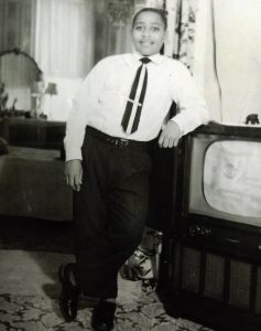Emmitt Till, wearing a tie and leaning against a tv
