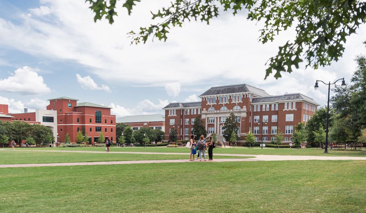 A wide view of a university campus's tall red brick buildings on a green expanse
