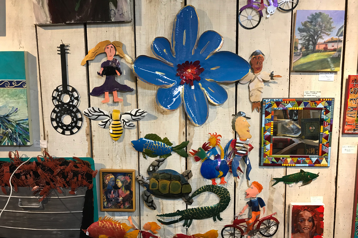 A wall of metal art, with a large blue flower piece as the main focus