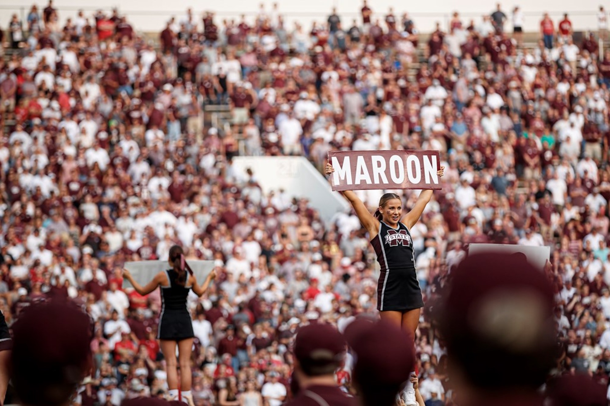 MSU cheerleaders are seen on field with fans in the football stadium behind them