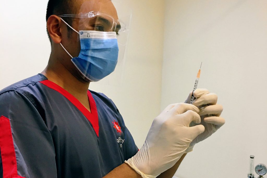 Physician readying a vaccination needle, inside a clinic