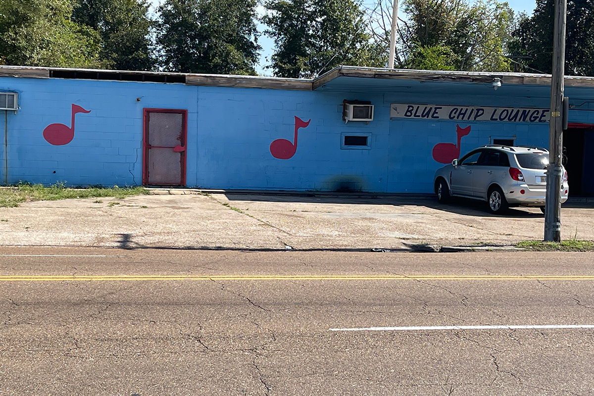 A long short blue building with red music notes painted and a sign that says Blue Chip Lounge