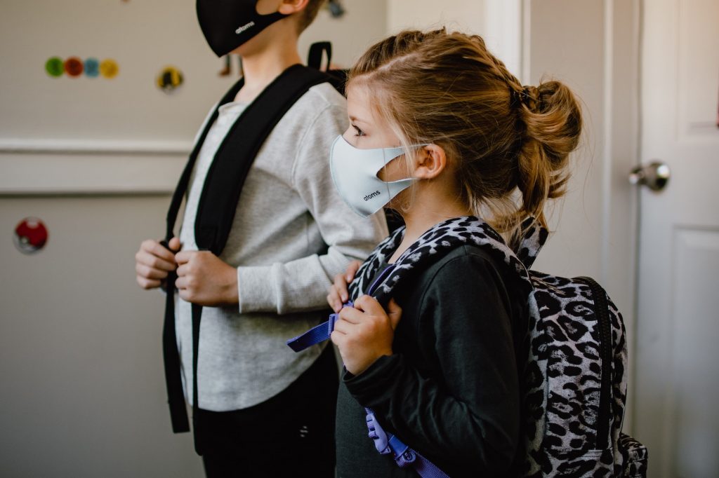 a photo of two children in masks with backpacks on in the age group that Pfizer has asked the FDA to approve the COVID vaccine for