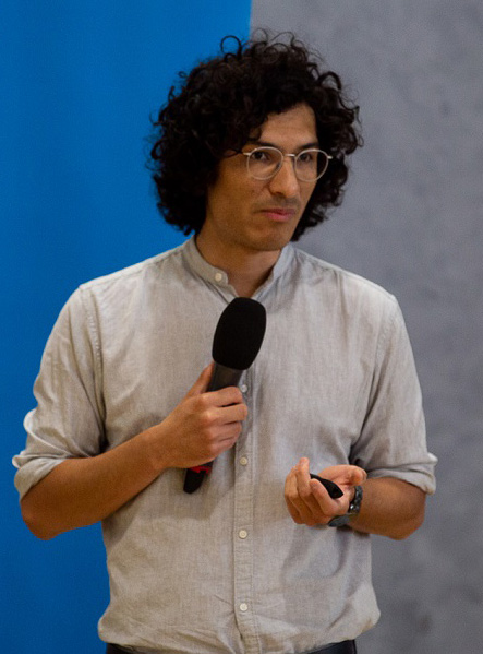 Ray Serrato speaking at a conference, mic in hand