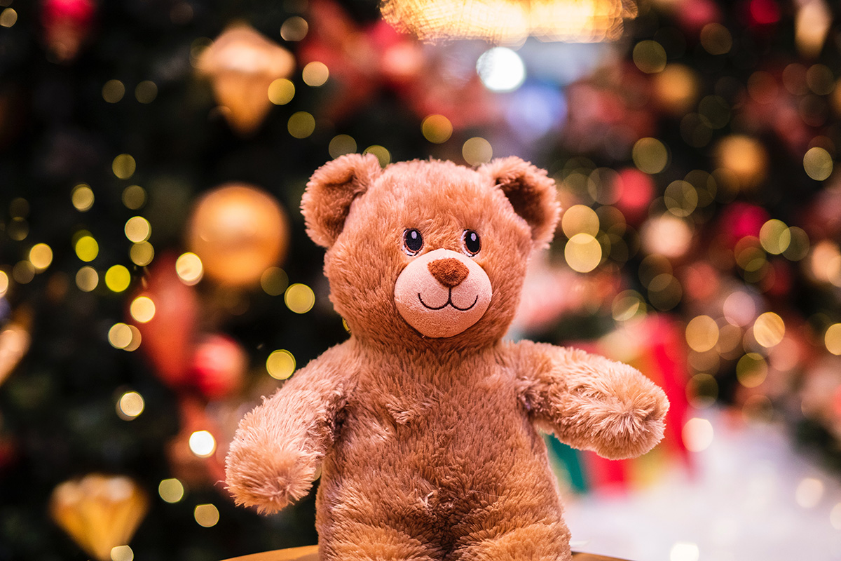 Brown plush teddy bear with out of focus lights behind it