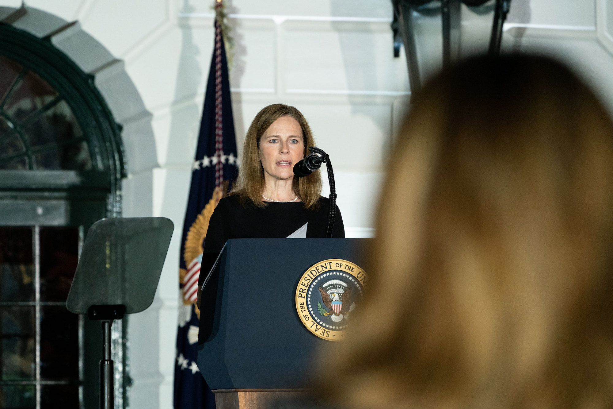 A photo of Amy Coney Barrett standing in front of the presidential seal