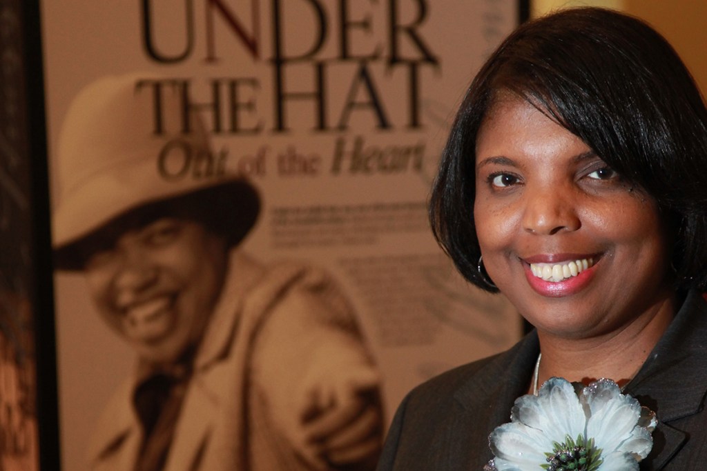 Photo of a smiling woman wearing a black jacket with a large white flower on the lapel