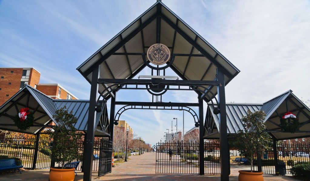 a photo of an academic building with students standing on a campus crosswalk in front of it